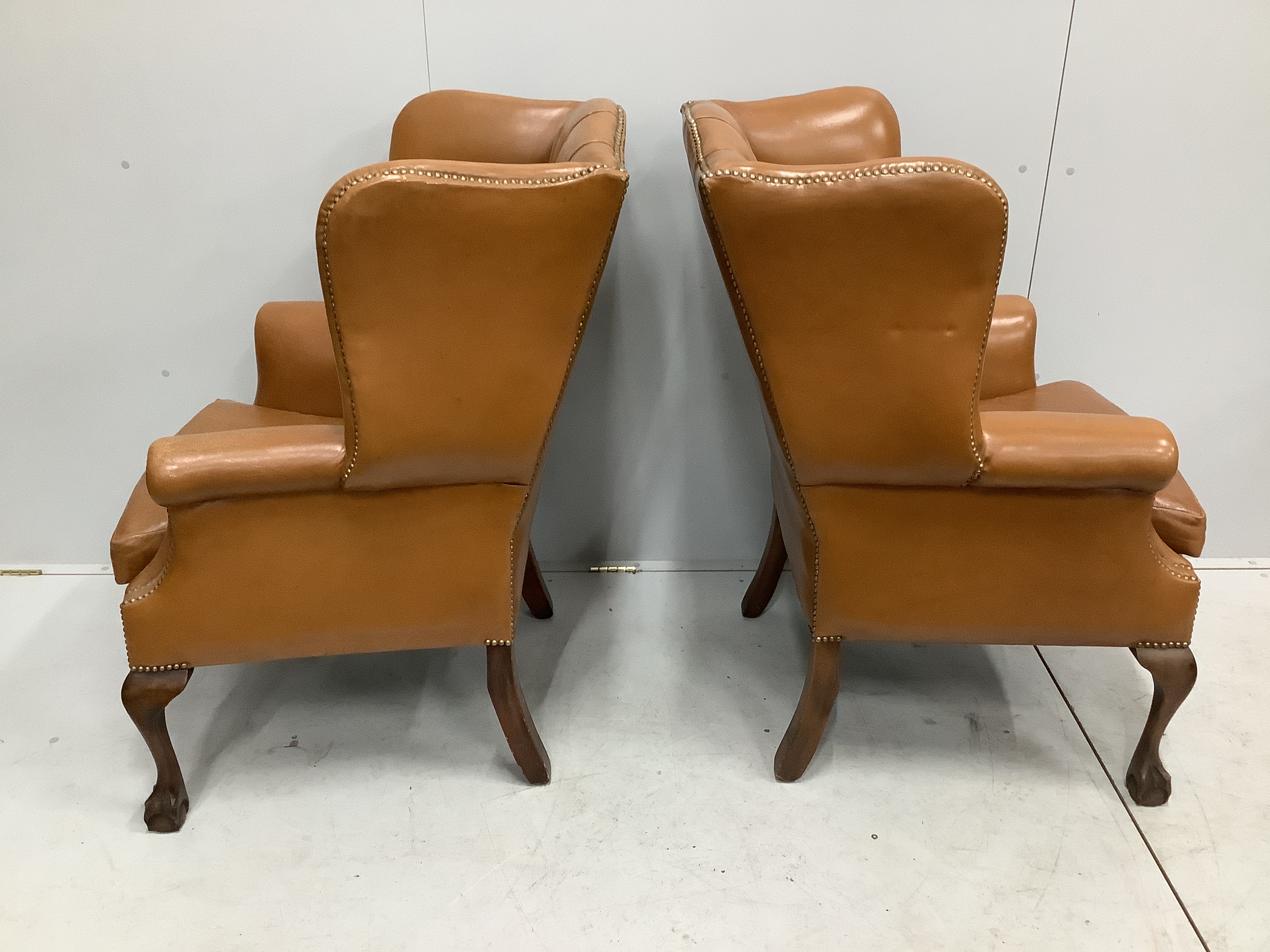 A pair of reproduction George III style buttoned pale brown leather wing armchairs, width 75cm, depth 66cm, height 107cm